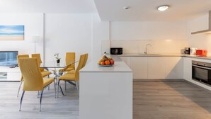 A modern kitchen with white cabinetry, a central island, and a dining area with yellow chairs. - RDR450 - Beautiful family apartment in Benahavis (Benahavís)