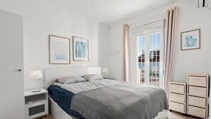 A modern bedroom with a bed, bedside tables, and a view of the outside.