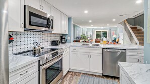 A modern kitchen with white cabinets, stainless steel appliances, and a marble countertop. - Relaxing Oceanfront Escape w/ 2 Bedrooms & Fenced-in Backyard (Hilton Head Island)