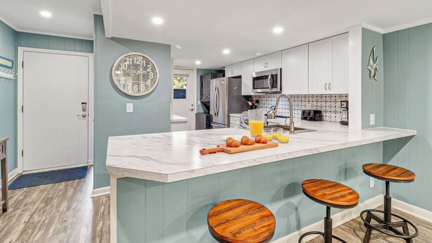 A modern kitchen with a marble island, stainless steel appliances, and wooden bar stools. - Relaxing Oceanfront Escape w/ 2 Bedrooms & Fenced-in Backyard (Hilton Head Island)