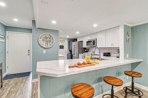 A modern kitchen with a marble island, stainless steel appliances, and wooden bar stools.