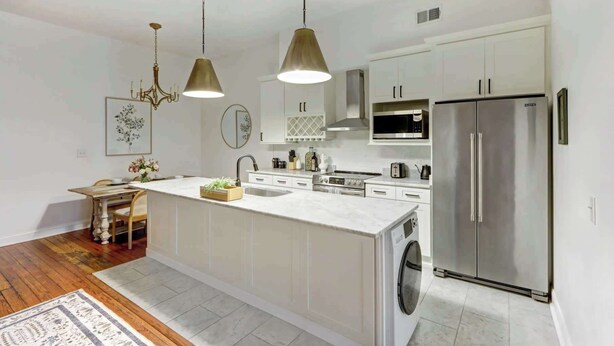 A modern kitchen with white cabinetry, stainless steel appliances, and pendant lighting. - A State of Mind, Modern | Historic | Central (Savannah)
