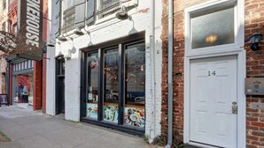 A storefront with a large glass window, a door with the number 14, and a brick wall. - A State of Mind, Modern | Historic | Central (Savannah)