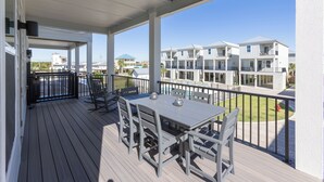 Una terraza cubierta al aire libre con una mesa y sillas, con vista a una zona residencial con edificios de varios pisos.