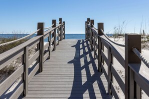 A wooden boardwalk leading to the beach with railings on both sides.