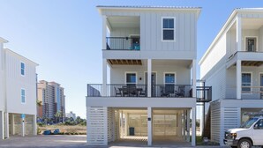 Un edificio residencial de varios pisos con un balcón en el nivel superior, entrada de garaje y una camioneta estacionada.