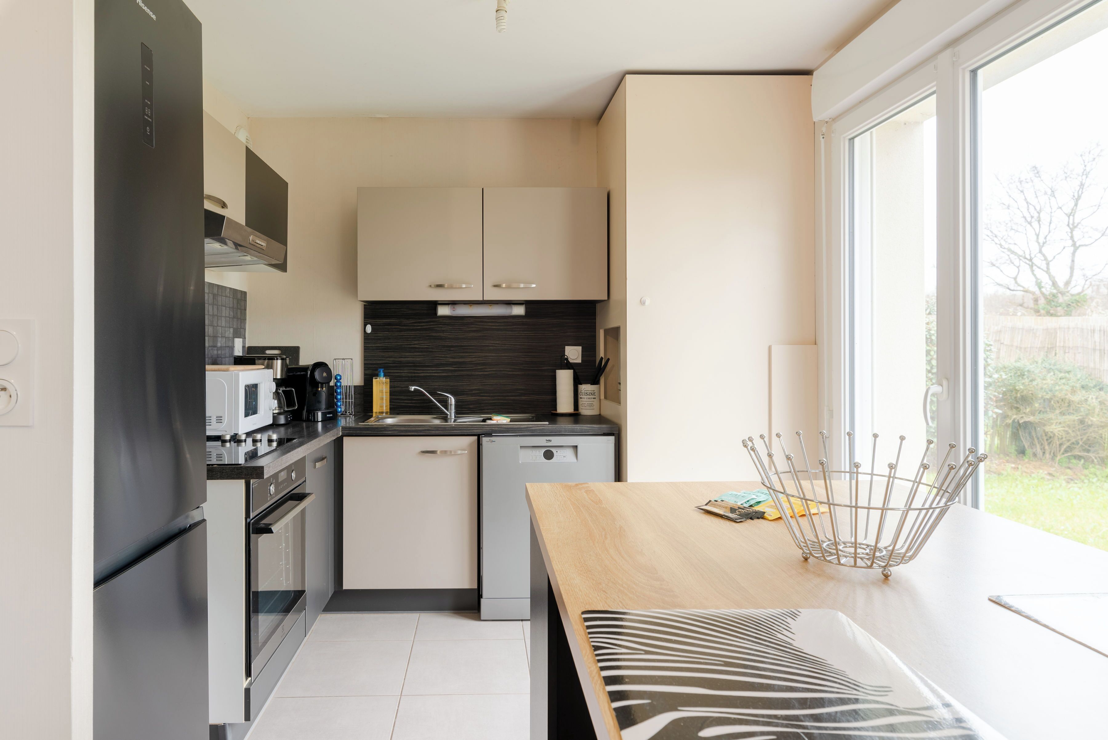 Een moderne keuken met roestvrijstalen apparatuur, een vaatwasser en een raam met uitzicht op de omgeving.