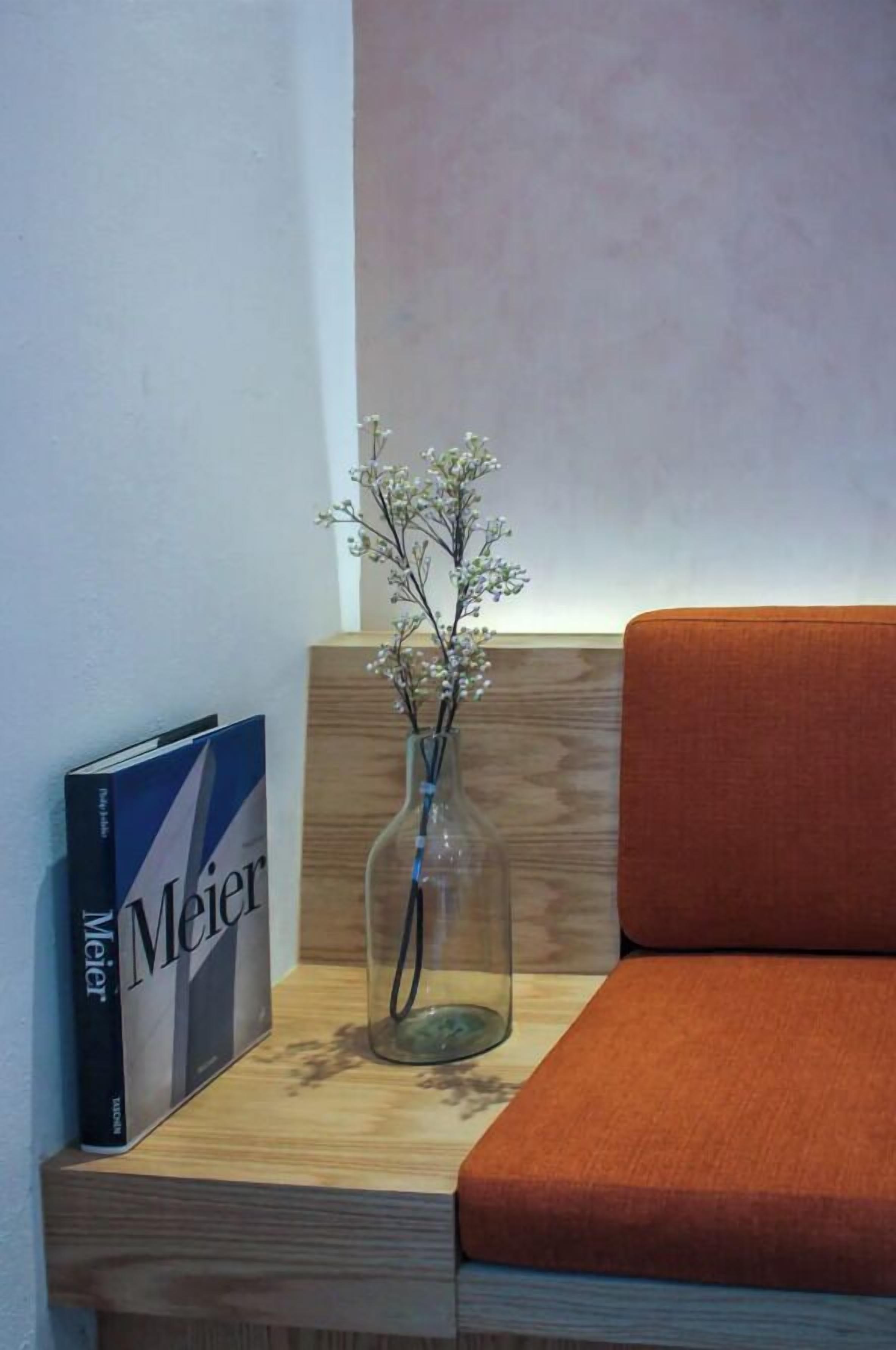 Ein Holzregal mit einem Buch mit dem Titel 'Meier' und einer Vase mit Blumen.