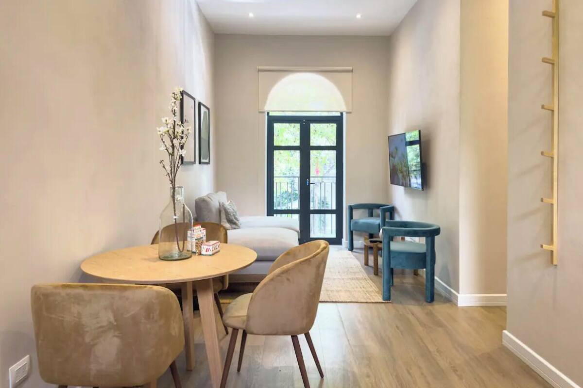 A modern living room with a sofa, a coffee table, and a TV mounted on the wall.