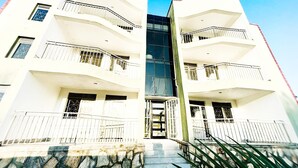 A modern two-story building with balconies, a central entrance, and a stone facade. - 1 Bedroom Apartment Palm-View Balcony Entebbe (Nkumba)