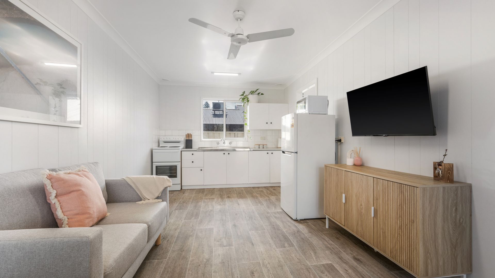 A modern kitchen with white cabinetry, a built-in oven, and a large window.