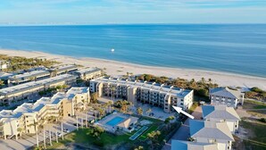 Un hotel fronte spiaggia con diversi edifici, una piscina e vista sulla spiaggia.