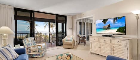 A spacious living room with a balcony, a television, and a dining area.