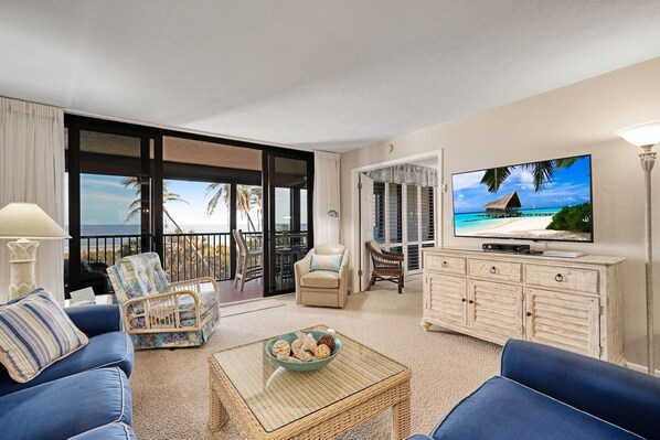 A spacious living room with a balcony, a television, and a dining area.