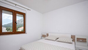 A bedroom with a bed, a window, and a view of a mountain. - Modern 2-Bedroom Apartment for up to 6 persons. (Orebic)