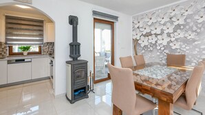Een moderne keuken met een inbouwfornuis, een eethoek met een glazen tafel, en een decoratieve wand met witte bloemen.