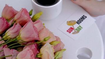 Een dienblad met een boeket roze en witte rozen, een kop koffie en een kaartje met de tekst