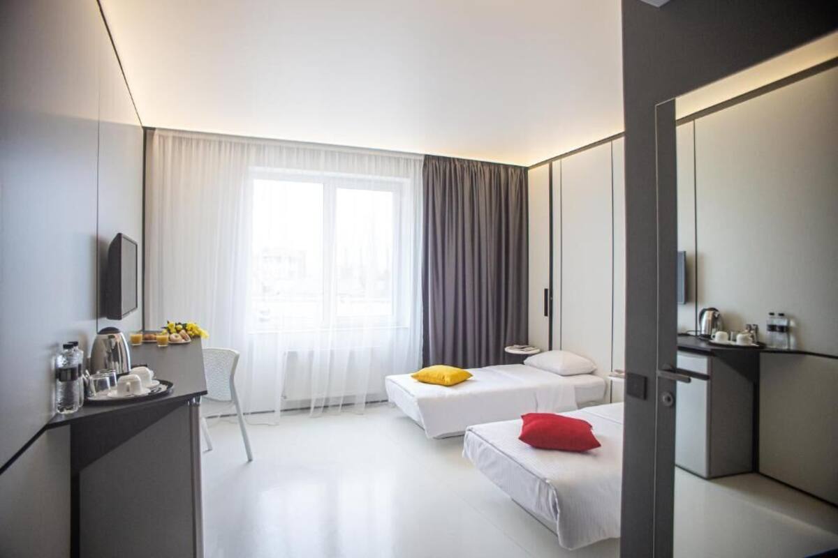 A modern hotel room with a bed, bedside table, and a desk area with a chair.