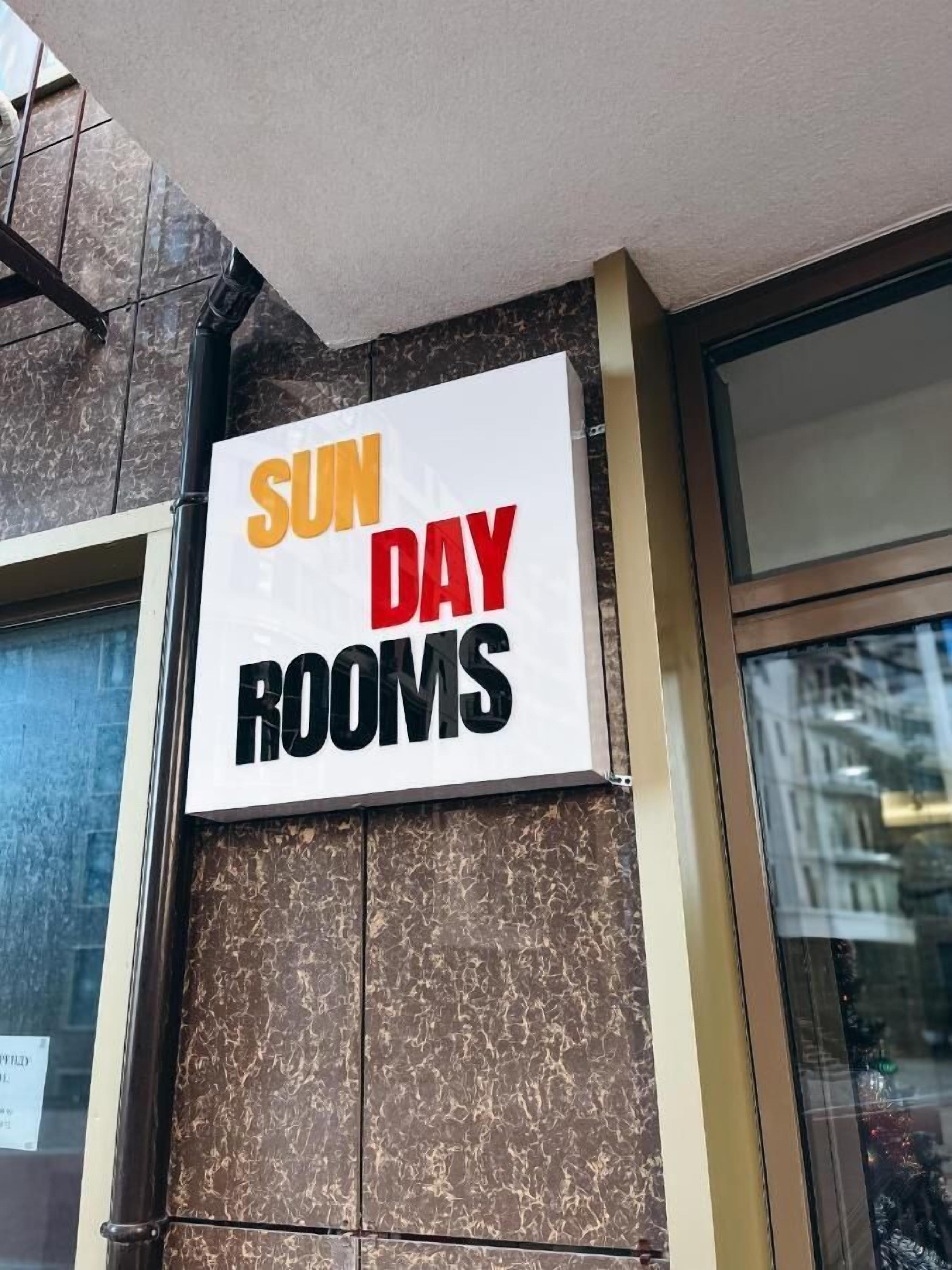 A sign advertising 'SUN DAY ROOMS' on a building facade.