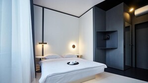 A modern bedroom with a large bed, bedside tables, a wall-mounted shelf, and a door.