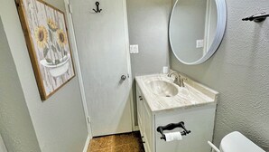 Un baño con lavamanos, inodoro y espejo.