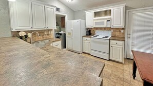 Una cocina con armarios blancos, encimera de granito, microondas integrado y estufa.