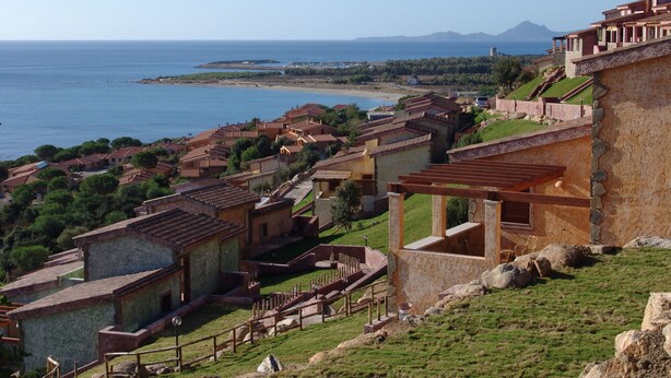 A coastal village with traditional architecture, terraced houses, and a view of the sea and distant mountains. - Villino Trilocale Apartments Seaside (Villaputzu)