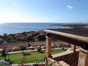 A coastal view with a clear sky, a beach, and a residential area with terracotta roofs. - Villino Trilocale Apartments Seaside (Villaputzu)