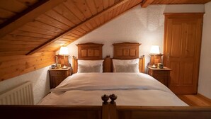 A bedroom with a sloped wooden ceiling, a wooden bed frame, two bedside tables with lamps, and a wooden wardrobe. - Chalet Zala, Garden, Terace, EVcharger, Sauna, Jacuzzi  (Jesenice)