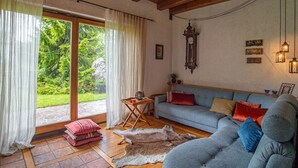 A cozy living room with a blue sofa, a wooden coffee table, and a large window with curtains. - Chalet Zala, Garden, Terace, EVcharger, Sauna, Jacuzzi  (Jesenice)