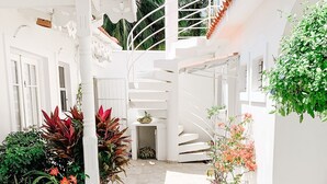 Un patio estrecho con baldosas, paredes blancas y una escalera de caracol.