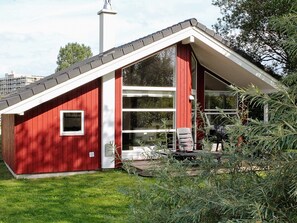 Ein rotes Gebäude mit einem geneigten Dach, großen Fenstern und einer kleinen Veranda mit Stühlen.