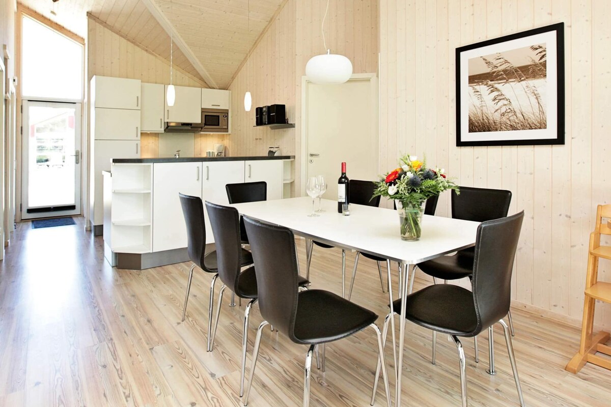A modern kitchen with white cabinets, a microwave, and a hanging light fixture.