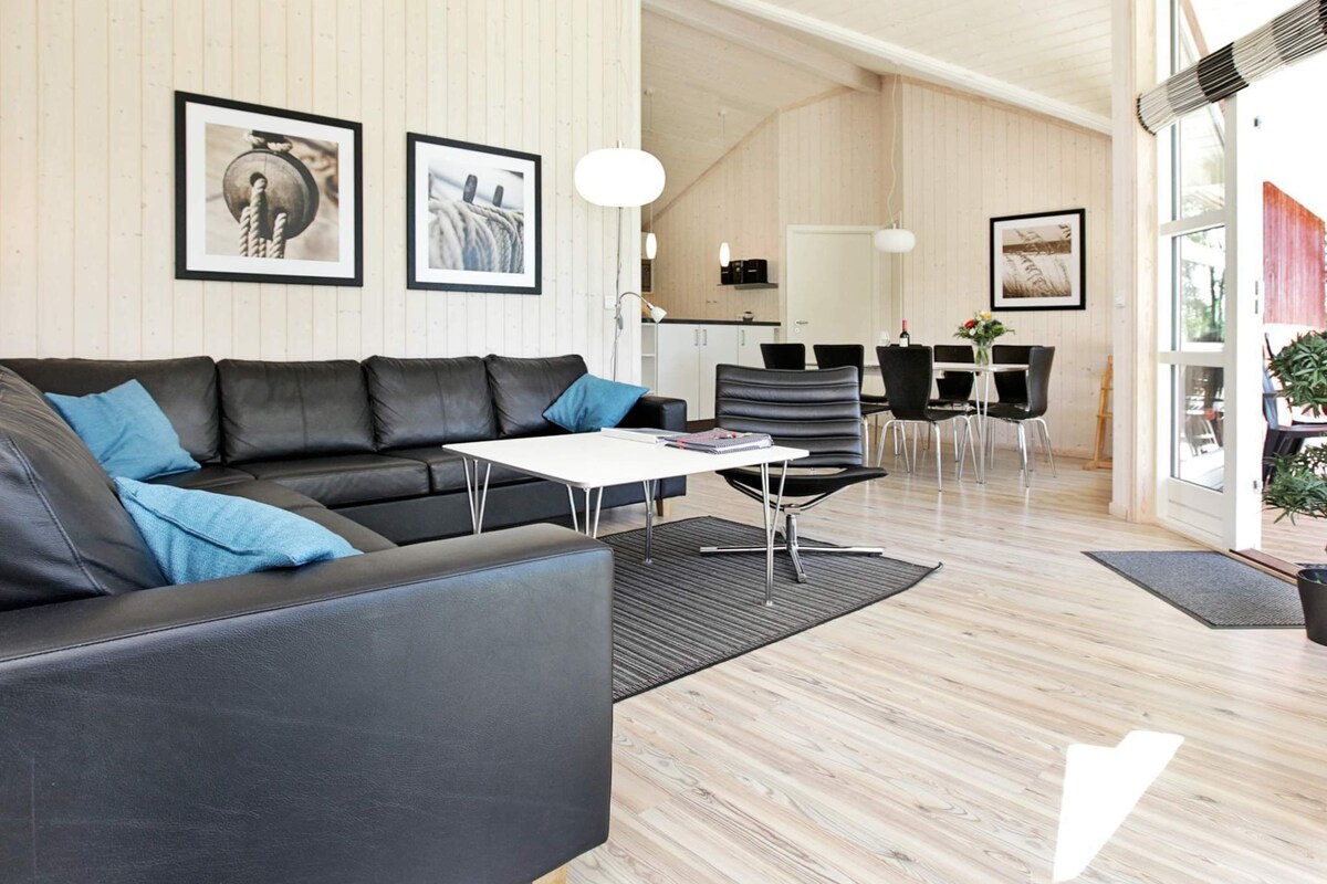 Ein modernes Wohnzimmer mit einer schwarzen Ledersofa, einem weißen Couchtisch und einem Essbereich mit weißem Tisch und Stühlen.