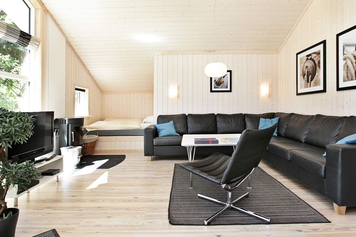 A modern living room with a sofa, a dining table, a TV, and a fireplace.