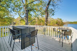 Une terrasse dotée de mobilier d’extérieur, d’une rambarde et offrant une vue sur les arbres et l’eau.