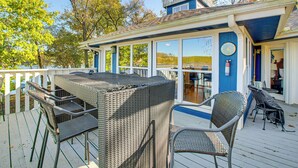 En overdækket terrasse med spisebord og stole, med udsigt over vandet.