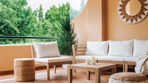 A sunlit patio with a sofa, two chairs, a small table, and a round ottoman. - Malvón by BH Marbella  (Marbella)