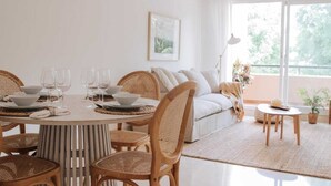 A dining area with a round table set for four, surrounded by wicker chairs. A sofa and a small round table with a lamp are visible in the background. - Malvón by BH Marbella  (Marbella)