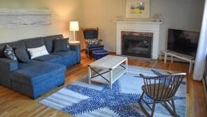 A living room with a sofa, a chair, a coffee table, a fireplace, and a television. - 3 bedroom home, quick drive to Northside Beaches (Dennis)
