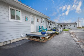 A row of mobile homes with a porch, a blue chair, and a potted plant.