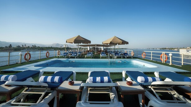 A poolside area with lounge chairs, umbrellas, and lifebuoys. - Orient Nile Romance Nile Cruise - Every Saturday from Luxor for 07 & 04 Nights - Every Wednesday From Aswan for 03 Nights (Luxor)