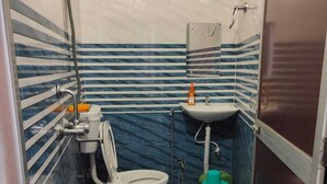 Un baño con inodoro, bidé y lavamanos, con azulejos blancos y azules a rayas.