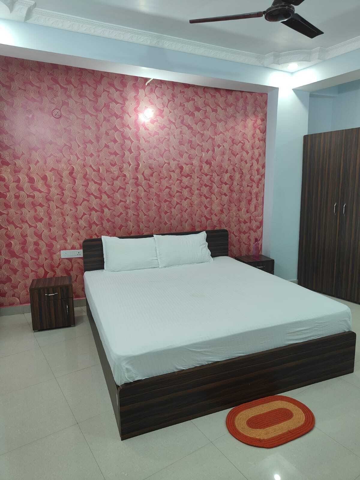Une chambre à coucher avec un grand lit, une armoire, une table de chevet et un ventilateur de plafond.