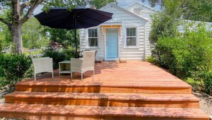 A wooden deck leading to a house with a blue door, surrounded by greenery. - A Walk in the Pines - Bright & Cute 3br 2ba Home (North Charleston)