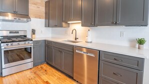 A modern kitchen with grey cabinets, a stainless steel stove, and a dishwasher. - A Walk in the Pines - Bright & Cute 3br 2ba Home (North Charleston)