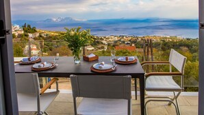 Une table dressée pour deux personnes, avec vue sur la mer et les montagnes.