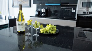Un comptoir de cuisine avec une bouteille de vin, deux verres et une assiette de raisins.