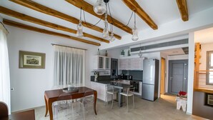 Une cuisine moderne dotée d’un îlot central, de poutres en bois et de luminaires suspendus.