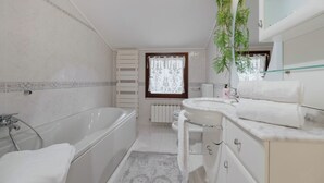 Uma casa de banho moderna com banheira, lavatório e sanita.